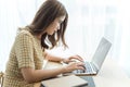 Entrepreneur concept a young female freelancer working on her laptop device typing an urgent document seriously