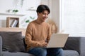 Entrepreneur handsome business asian man wear shirt sitting on couch working online with computer laptop smile happiness and relax Royalty Free Stock Photo