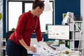 Entrepreneur leaning over desk looking at charts on desktop computer screen