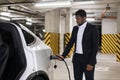 Entrepreneur plugging in charging cable into EV at parking Royalty Free Stock Photo