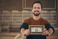 Entrepreneur showing framed bank note with a proud smile