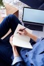 Entrepreneur or student working and writing at paper notebook, using laptop in a comfortable homey atmosphere. Close up of hands m