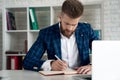 Entrepreneur writing notes sitting at his desk. Young man making business plans with papers and computers on his desk Royalty Free Stock Photo