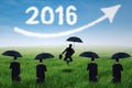 Entrepreneurs with umbrella and numbers 2016 at field