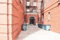 Entry door of orange brick old buildings with fire stairs, and garbage cans during the day. Travel and housing concepts. Bronx, Royalty Free Stock Photo