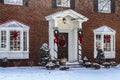 Entry and porch to traditional Georgian style brick house with columns and bay windows decorated for Christmas in the snow Royalty Free Stock Photo