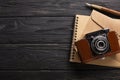 An envelope, a beautiful camera and a notebook with a pen on a black wooden background with a place for an inscription Royalty Free Stock Photo