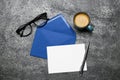 Envelope with blank paper card, cup of coffee, pen and glasses on grey table, flat lay Royalty Free Stock Photo