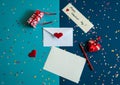 An envelope, a blank sheet of paper, a pencil, a gift box, a hand-sewn heart with ribbons and lace, a scattering of colored confet