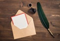 Envelope with empty card and quill pen on wooden table Royalty Free Stock Photo
