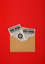 Envelope with FAKE NEWS newspapers over red Royalty Free Stock Photo