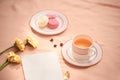 Envelope, flowers, and macarons with cup of tea