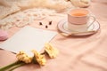 Envelope, flowers, and macarons with cup of tea on light background