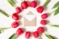 Envelope and frame of red tulips on white wooden background. Flat lay with copy space Royalty Free Stock Photo