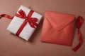 Envelope and gift box with red ribbon on a brown background Royalty Free Stock Photo