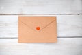 Envelope with a letter and red heart lies on a white wooden back