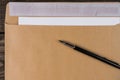 Envelope nested in it leaves lying on vintage wooden table. The fountain pen is opened and ready for writing . Royalty Free Stock Photo