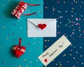 An envelope, a note with a wish, a gift box, a hand-sewn heart with ribbons and lace, a scattering of colorful confetti on a blue Royalty Free Stock Photo