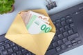 envelope salaries under the table. Golden envelope with cash euro banknotes on computer keyboard. Bribery, salary, wage