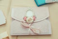 an envelope with soft pink embossing, decorated with a light pink ribbon, artificial roses Royalty Free Stock Photo