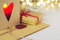 Envelope with wax seal surrounded by gift and a candle in the wooden box with heart shaped hole