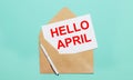 Envelope, a white pen and a white sheet of paper with the text HELLO APRIL Royalty Free Stock Photo