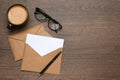Envelopes with blank paper card, cup of coffee, glasses and pen on wooden table. Space for text Royalty Free Stock Photo