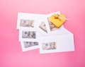 Envelopes with dollar bills and gift box on pink background. Business bonus and bribes concept Royalty Free Stock Photo