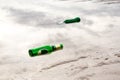 Envelopment concept, Empty green beer bottle on the beach. Royalty Free Stock Photo