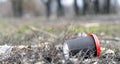 Enviromental pollution; paper cup for coffee and red plastic cover on a background of forest nature and grass.