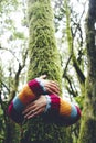Environment and nature care people concept activity. One woman hugging and embracing green musk covered trunk tree in the forest Royalty Free Stock Photo