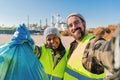 A environmental activist or volunteer multiracial couple picking up trash og the beatch, and taking a selfie portrait Royalty Free Stock Photo