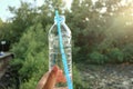 A female hand holding a plastic bottle of drinking water with blur green nature background Royalty Free Stock Photo