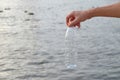 A man hand holding a plastic bottle of drinking water into a river with water background