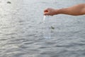A man hand holding a plastic bottle of drinking water into a river with water background