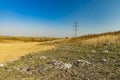 Environmental disaster garbage polluted field country side space summer time horizon background with power line high voltage wires Royalty Free Stock Photo