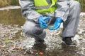 An environmental laboratory specialist in a protective suit lids a glass container with a soil sample for research