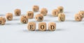 wooden cubes with the word EOD stand on a financial background, business concept