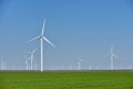 Eolian farm renewable energy in fresh green field against clear blue sky