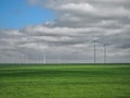 Eolian farm renewable energy in fresh green field against clear blue sky