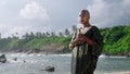 Epatage androgyne gay black man in luxury gown poses on scenic ocean beach. Non-binary ethnic fashion model in long posh