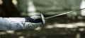 Epee of fencer with protected hand and arm against blurred background