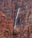 Ephemeral waterfall cascading down red sandstone cliffs in Southern Utah, USA