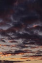 Epic dramatic sunset, sunrise sky with dark violet clouds in orange yellow sunlight