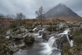 Epic landscape image of Buachaille Etive Mor waterfall in Scottish highlands on a Winter morning with long exposure for smooth