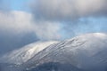 Epic landscape image of Skiddaw snow capped mountain range in Lake District in Winter with low level cloud around peaks viewed Royalty Free Stock Photo