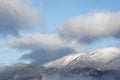 Epic landscape image of Skiddaw snow capped mountain range in Lake District in Winter with low level cloud around peaks viewed Royalty Free Stock Photo