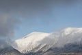 Epic landscape image of Skiddaw snow capped mountain range in Lake District in Winter with low level cloud around peaks viewed Royalty Free Stock Photo