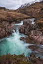 Epic landscape image of vibrant River Coe flowing beneath snowcapped mountains in Scottish Highlands Royalty Free Stock Photo