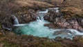 Epic landscape image of vibrant River Coe flowing beneath snowcapped mountains in Scottish Highlands